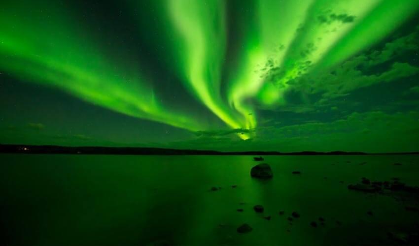 The aurora borealis lights up the sky over a lake.