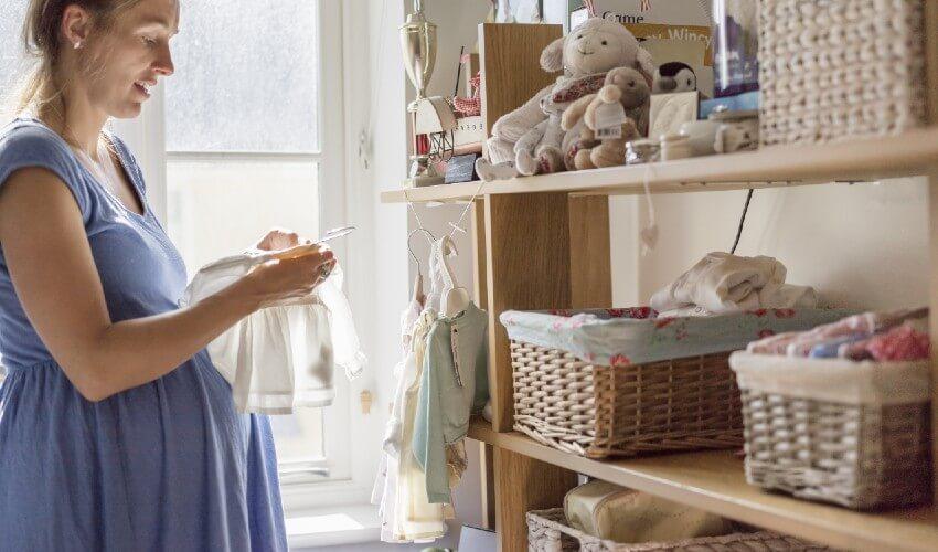A pregnant woman in a blue dress is looking at her phone.