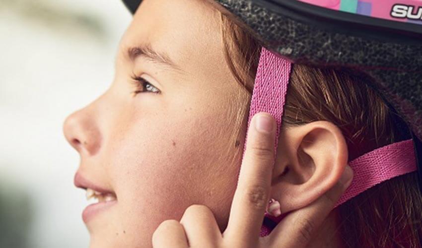 Girl adjusting the strap of her bicycle helmet.