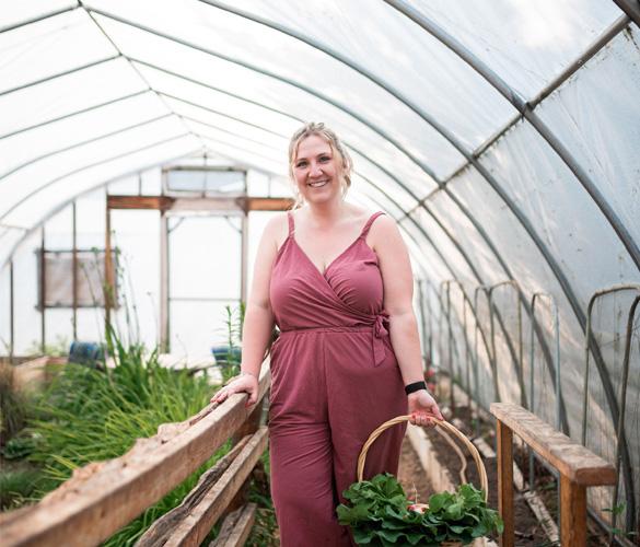 A woman in a pink jumpsuit holding a basket of vegetables.