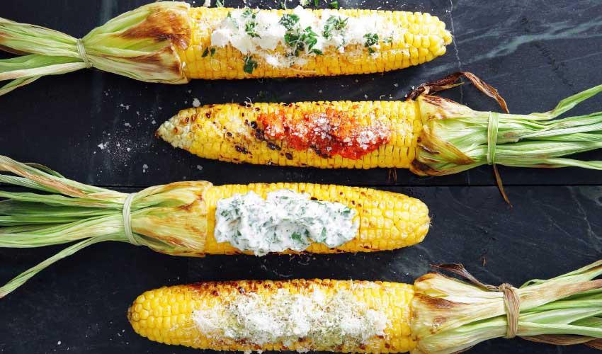 Grilled corn on the cob with sour cream and parsley.