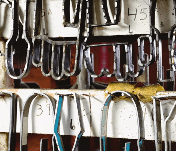Assorted shoe lasts of various sizes hanging on a wall.