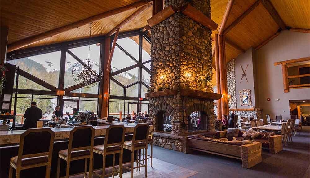 The lobby of a lodge with a large stone fireplace.
