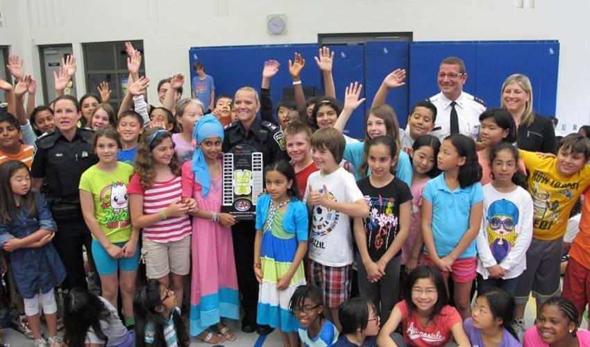 A group of children posing for a photo with a police officer.