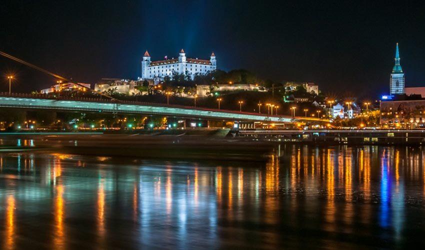 A city at night with a castle in the background.