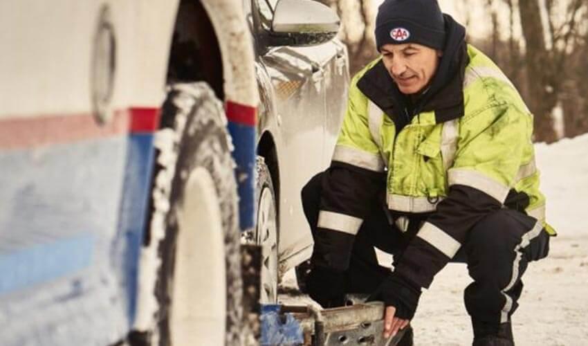 A man working on a car in the snow.