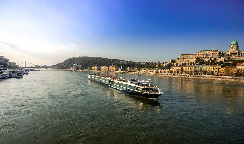 A boat is traveling down a river near a city.