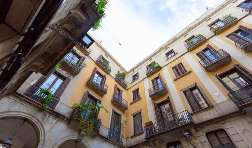 Low-angle view of a traditional european courtyard with balconies and potted plants.