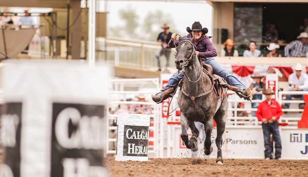 A cowboy is riding a horse at a rodeo.