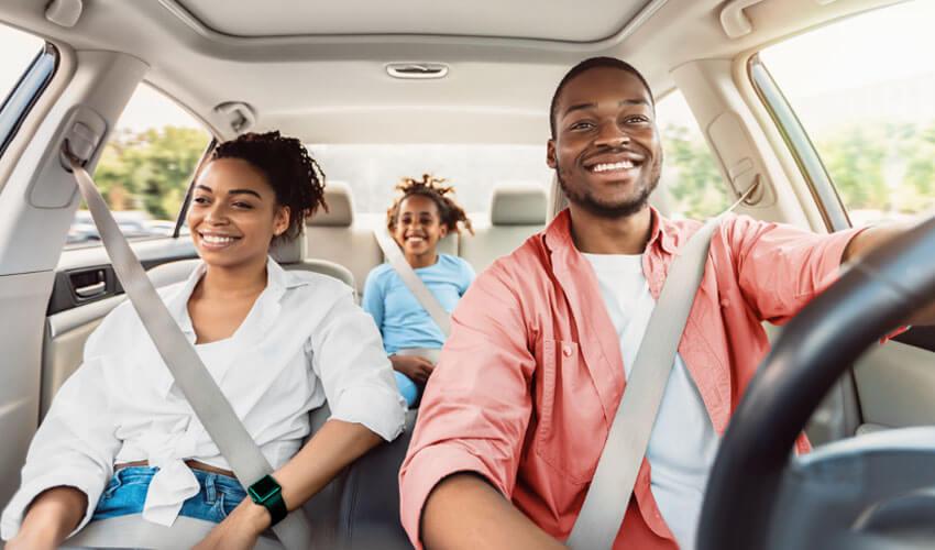 A family smiling while driving in a car.