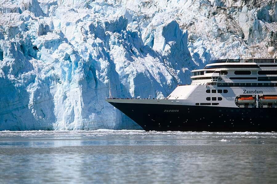 A cruise ship in front of a large glacier.