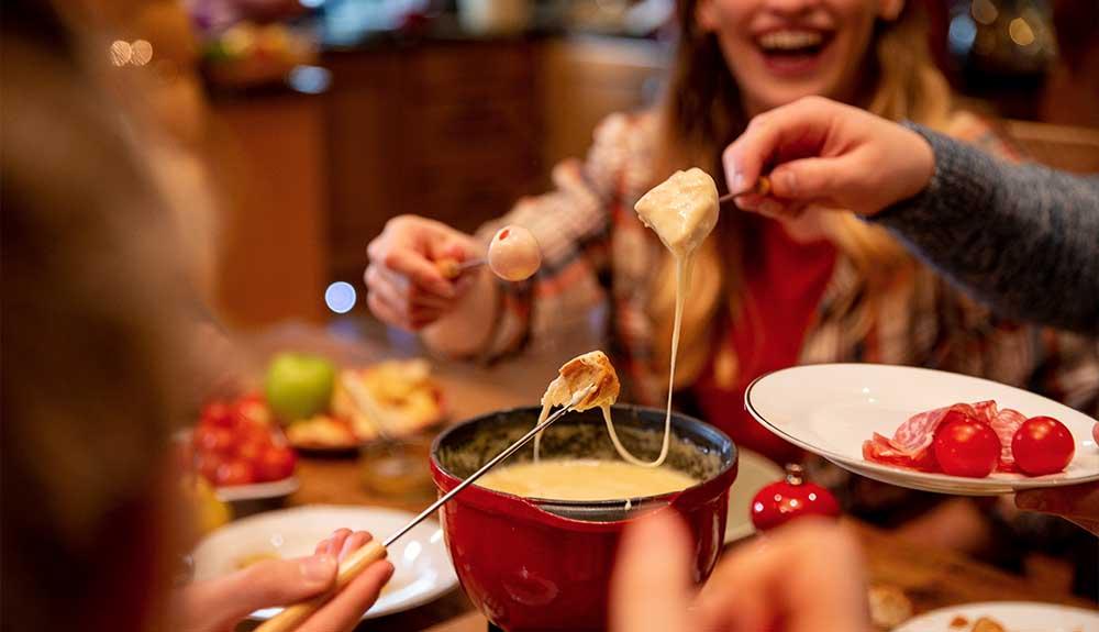 A group of people eating fondue at a table.