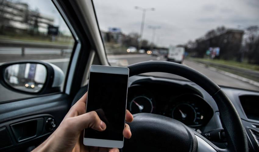 A person holding a cell phone while driving a car.