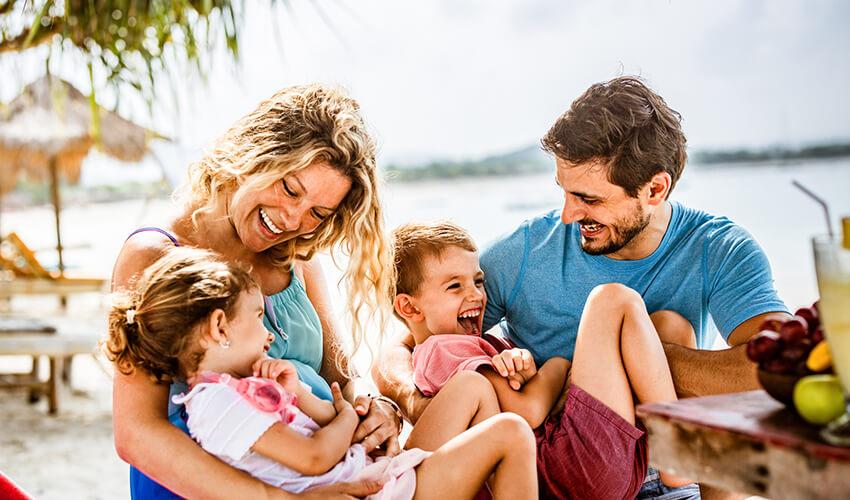 A family sits on a beach with their children.