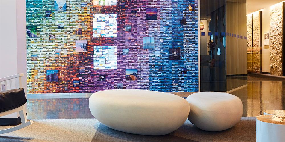 Modern lobby with a colorful mosaic wall art and oval-shaped seating.