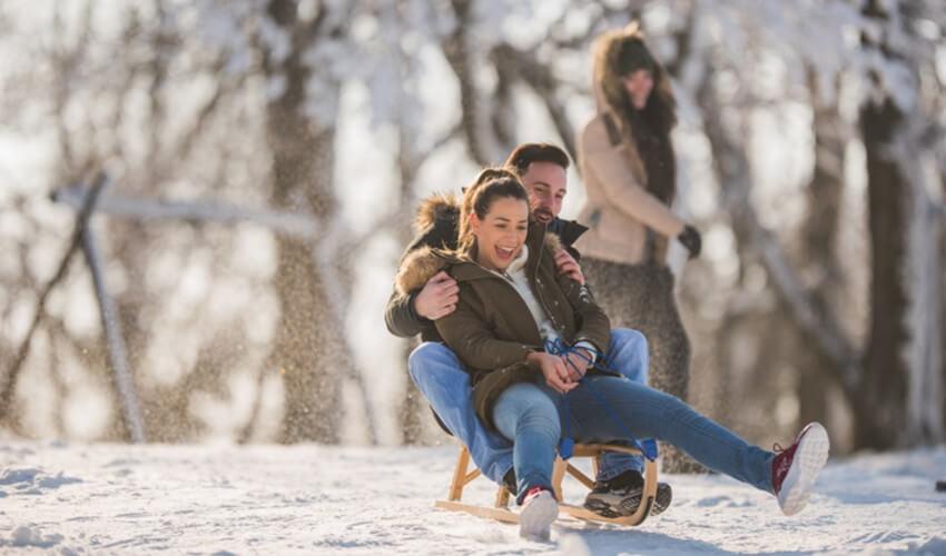 A group of people are sledding down a hill in the snow.