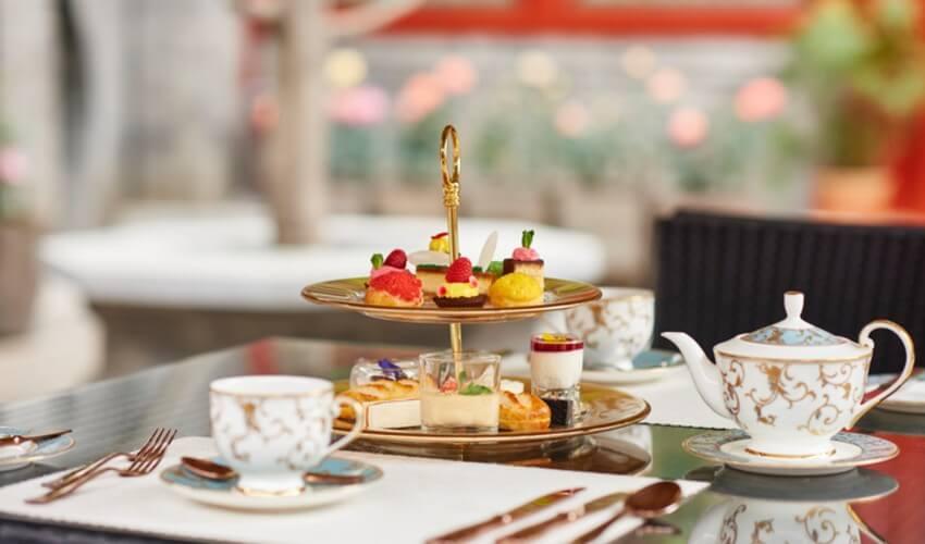 A three tiered tea set with cups and saucers on a table.
