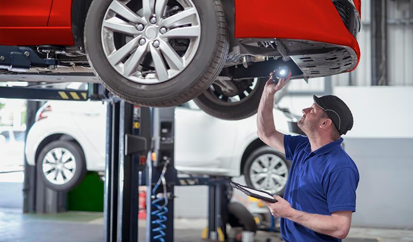 A mechanic inspecting the underside of a car.