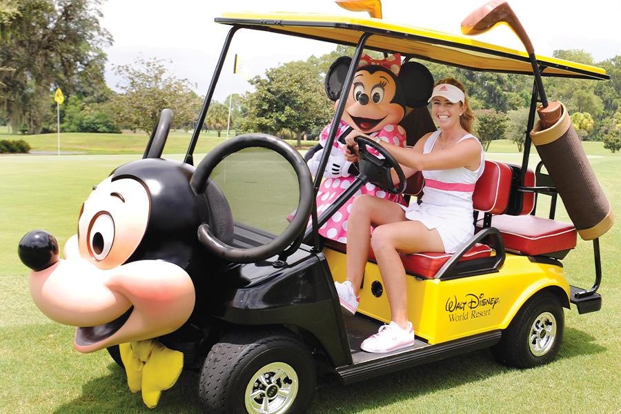 A woman in a golf cart with a cartoon character.