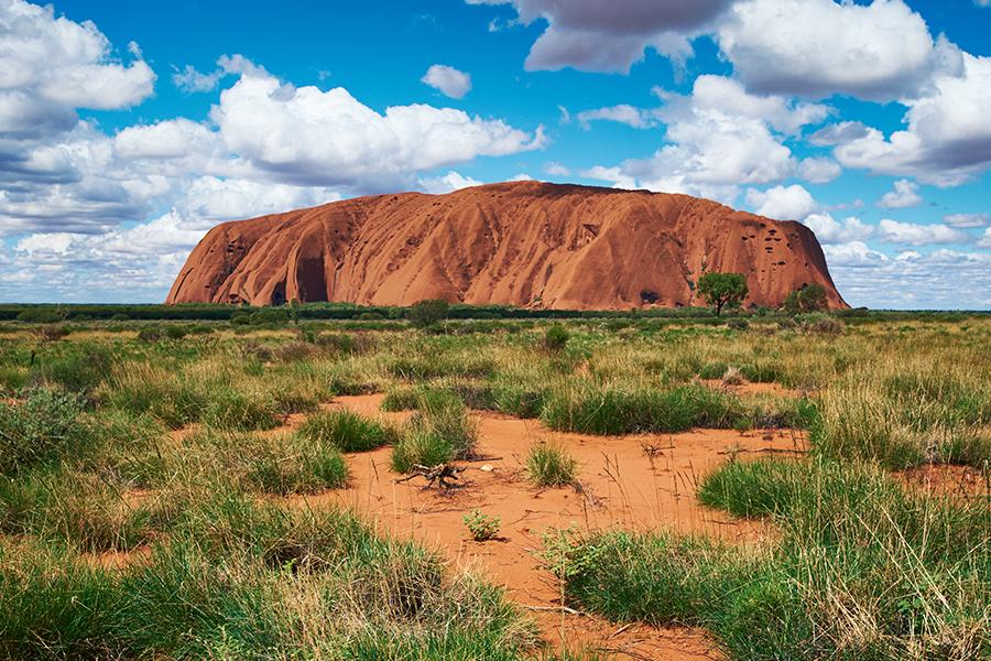 A large rock in the middle of a desert.