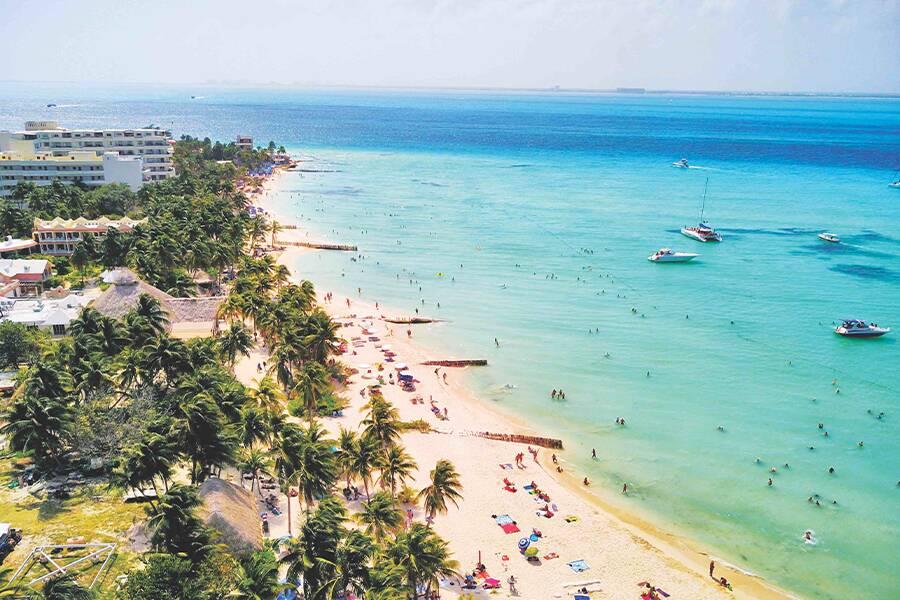 An aerial view of a beach with a lot of people and boats.