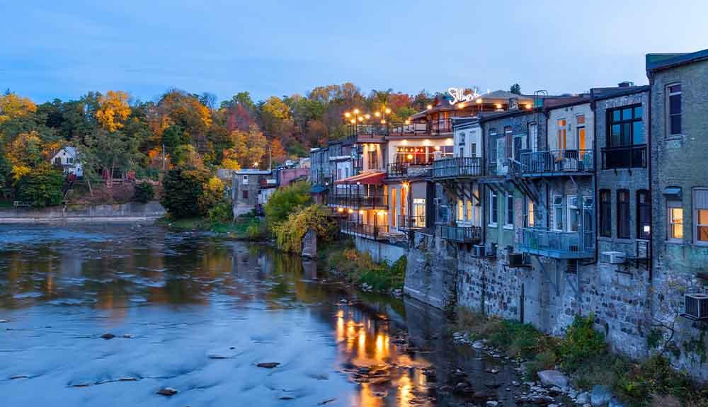 A row of houses along a river at dusk.