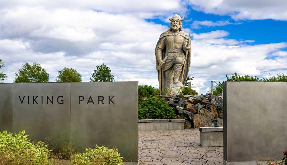 A statue of a viking in front of a sign.