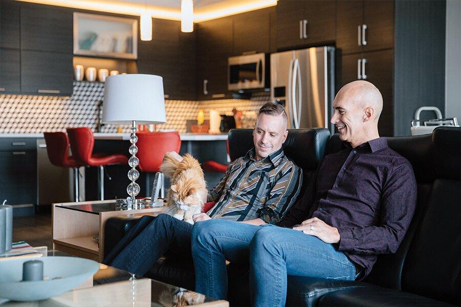 Two men sitting on a couch in a living room.