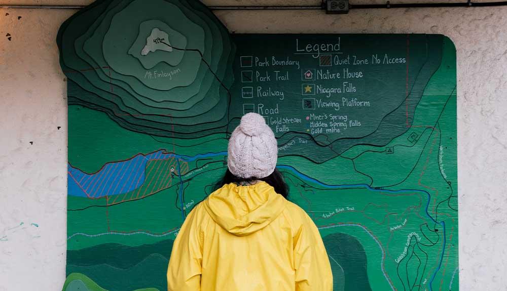 A woman in a yellow raincoat looking at a map.