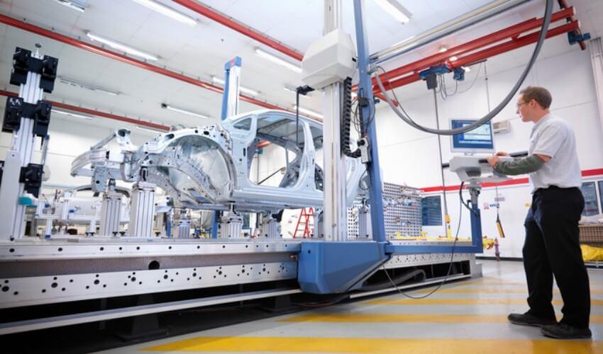 A man is working on a car in a factory.