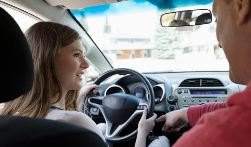A man and woman sitting in the driver's seat of a car.