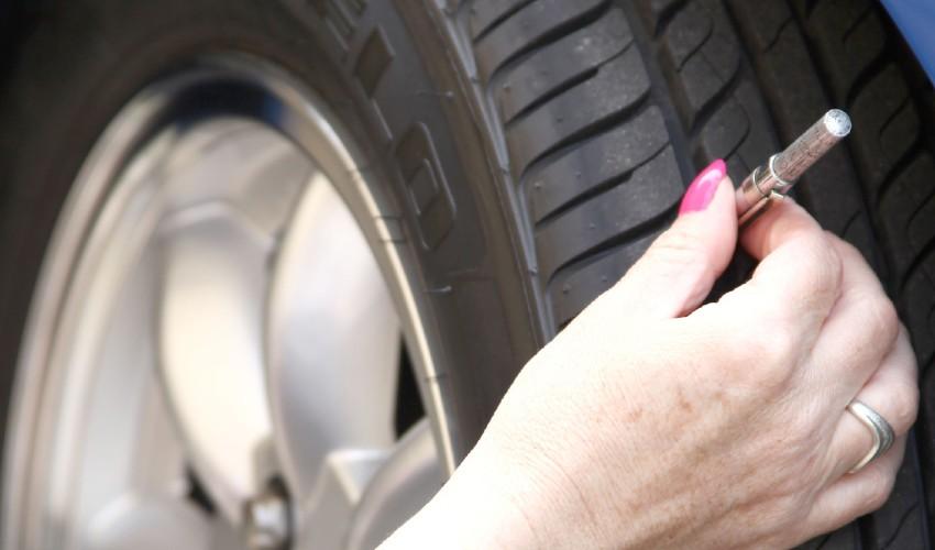 A woman is putting a tire on a car.